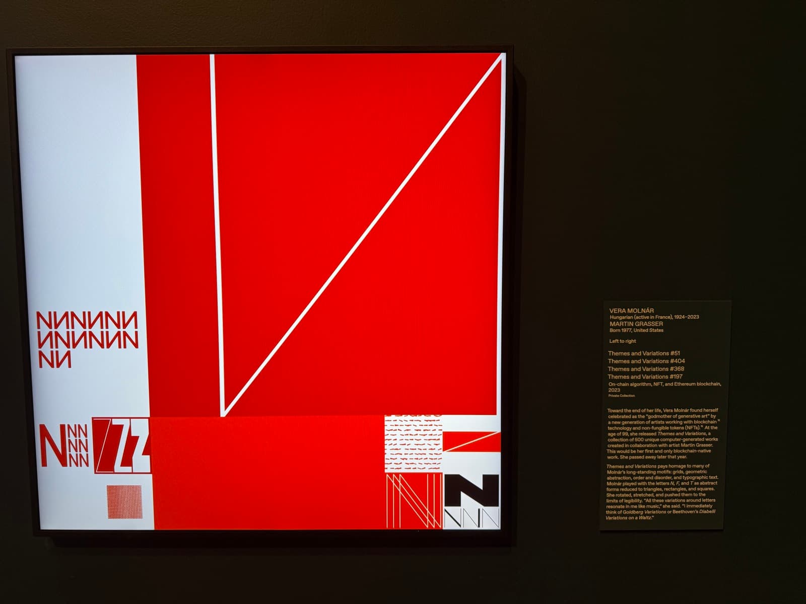 A gallery wall at the Toledo Museum of Art: a large red and white geometric composition from Vera Molnár's Themes and Variations, built from triangles, squares, and fields of the letters N and Z, beside its wall label.